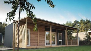 A modern single-story building with a covered porch, large windows, and a grassy yard. - Holiday Home in Olburgen With Terrace (Olburgen)