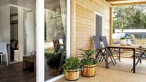 A wooden deck with a table and chairs, potted plants, and a sliding glass door leading to an interior room. - Holiday Home in Olburgen With Terrace (Olburgen)