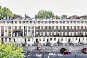 Una hilera de casas adosadas con arquitectura uniforme, una escalera central y un área de estacionamiento al frente.