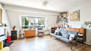 Amplia sala de estar con sofá, sillones, mesa de centro, estantería y un ventanal con vistas al exterior.
