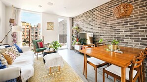 Un salon moderne avec un coin repas, un mur en briques et une grande fenêtre.