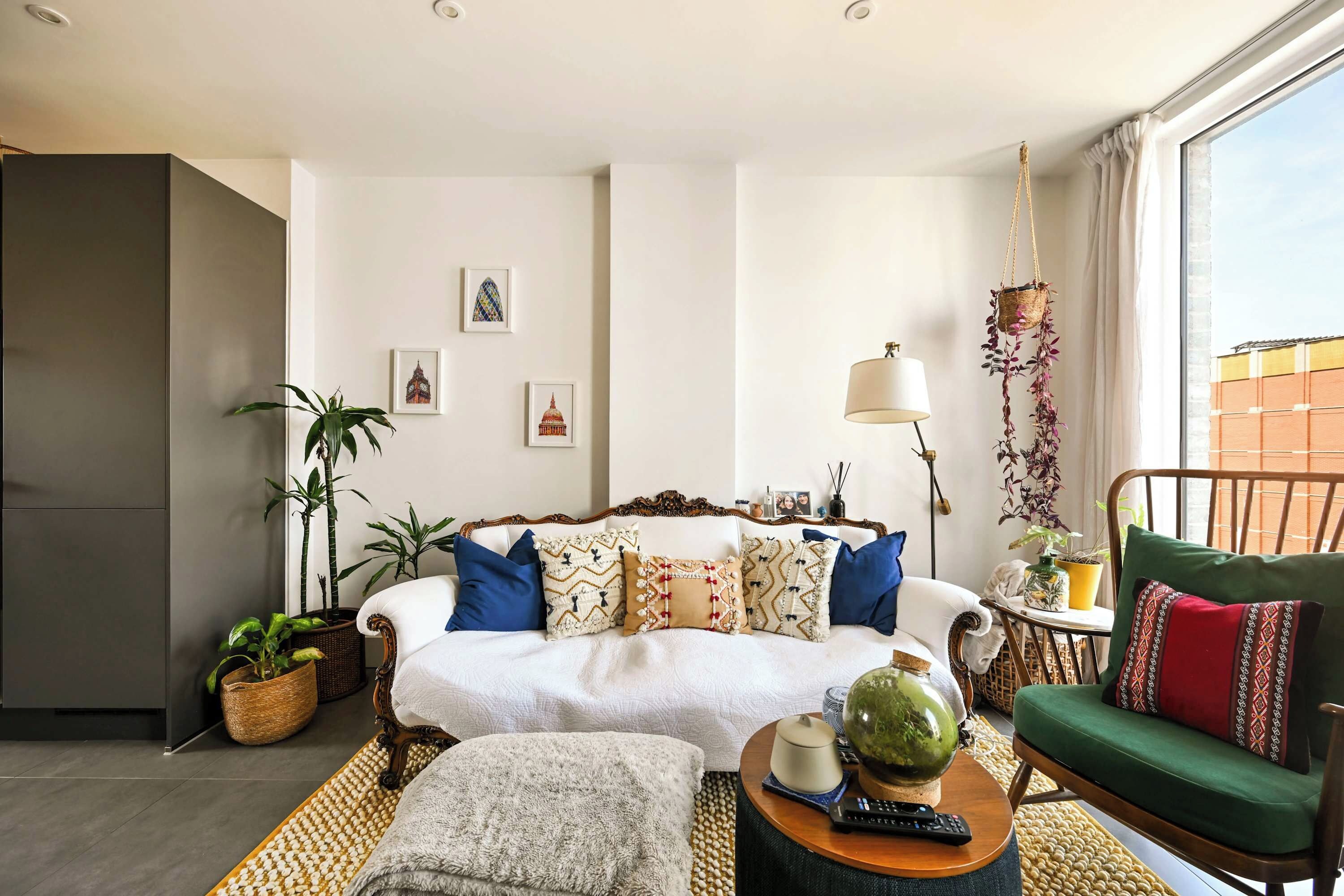 Ein Wohnzimmer mit Sofa, Sesseln, Couchtisch und Zimmerpflanzen.