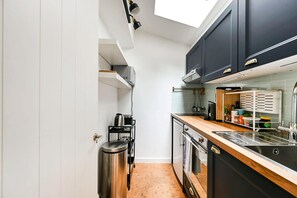 A modern kitchen with black cabinets, a stainless steel sink, and a wooden countertop. - The Artist's Studio in Notting Hill (Greater London)