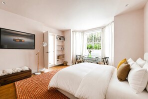 A bedroom with a bed, bedside tables, a desk, a chair, a window with curtains, and a bookshelf. - The Artist's Studio in Notting Hill (Greater London)
