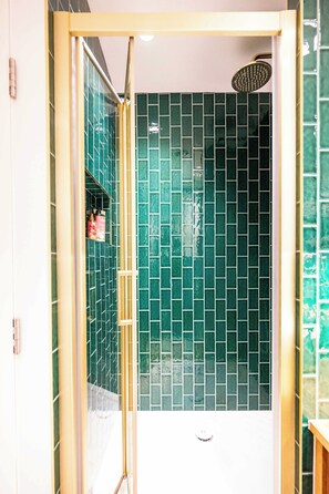 A shower with a glass door, green tiled walls, and a visible showerhead. - The Artist's Studio in Notting Hill (Greater London)