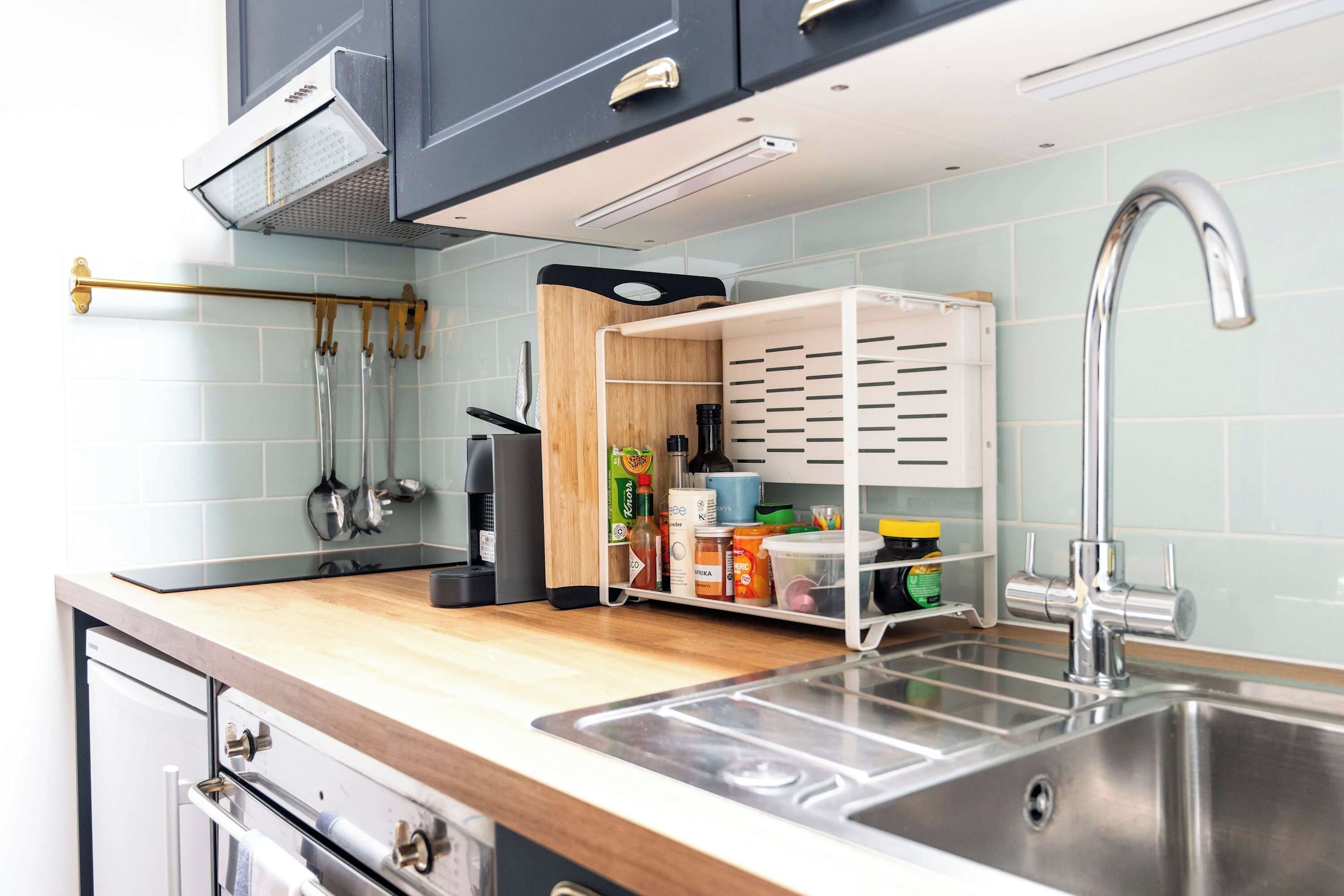 A kitchen with a stainless steel sink, a wooden countertop, and a built-in storage unit with shelves.