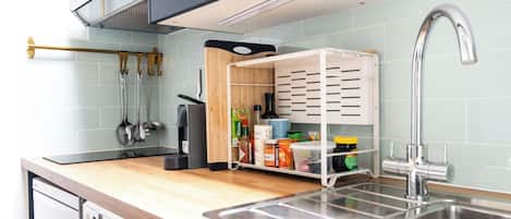 A kitchen with a stainless steel sink, a wooden countertop, and a built-in storage unit with shelves.