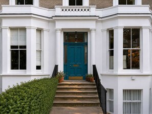 A building with a white facade, a blue door, and a staircase leading to the entrance. - The Artist's Studio in Notting Hill (Greater London)