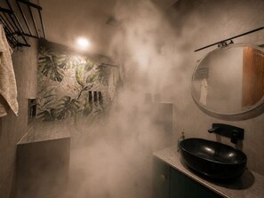 A bathroom with a round mirror, a black sink, and a wall with a tropical leaf pattern. - Luxurious 3-bedroom resort in Haridwar with Private pool, steam and jacuzzi (Haridwar)