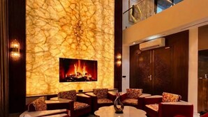 A modern living room with a fireplace, red sofas, and a marble wall. - Luxurious 3-bedroom resort in Haridwar with Private pool, steam and jacuzzi (Haridwar)