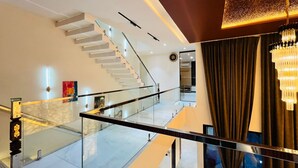 A modern interior with a glass railing, a staircase, and a chandelier. - Luxurious 3-bedroom resort in Haridwar with Private pool, steam and jacuzzi (Haridwar)