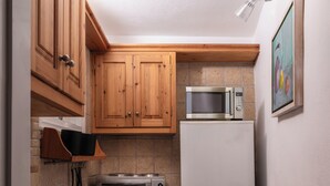 Une cuisine compacte dotée de meubles en bois, d’un four à micro-ondes, d’un grille-pain et d’un réfrigérateur.