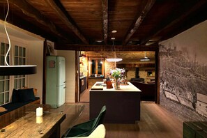 Eine rustikale Küche mit Holzbalken, einem Essbereich mit Tisch und Stühlen sowie einem Kühlschrank.