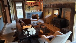 A rustic interior with a sofa, armchair, wooden coffee table, and a fireplace. - Château de Comborn Riverside Gite with Private River Access in the Vézère Valley (Orgnac-sur-Vézère)