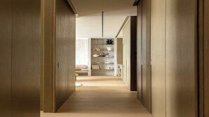 A modern hallway with wooden floors and walls, leading to a seating area with a sofa and a small table. - Luxury flat -2BR/6P-Madeleine/Saint Honore (Paris)