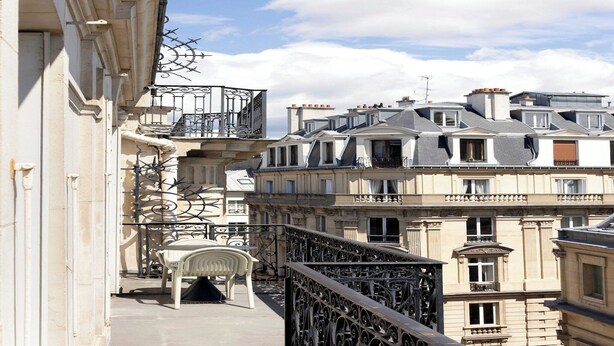 A balcony with a chair, wrought iron railing, and a view of adjacent buildings. - Luxury flat -2BR/6P-Madeleine/Saint Honore (Paris)