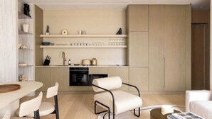 A modern kitchen with built-in appliances, a dining area with chairs, and a seating area with a sofa. - Luxury flat -2BR/6P-Madeleine/Saint Honore (Paris)