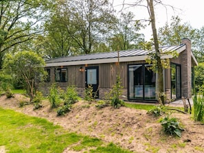Ein modernes Haus mit Metalldach, großen Fenstern und einer Ziegelaußenwand.