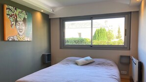 Ein Schlafzimmer mit großem Fenster, einem Bett, einem Bild an der Wand und einer Heizung.