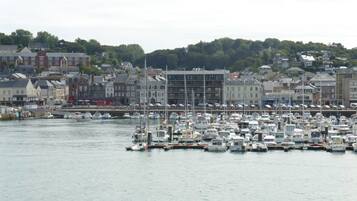 A marina with numerous boats docked, surrounded by buildings and a hilly backdrop.