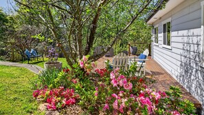 A garden with flowering plants and a patio area with outdoor furniture. - Wisteria Cottage in Leura (Leura)