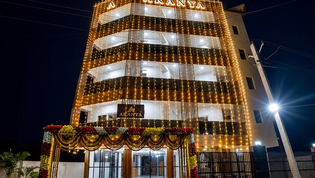Un immeuble à plusieurs étages dont la façade est illuminée et sur laquelle on peut lire le nom « ARANYA », avec une conception moderne caractérisée par des lignes verticales et une entrée fermée par un portail.