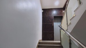 Un escalier aux marches en marbre foncé menant à une porte.