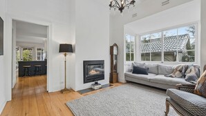 Un salon avec une cheminée, un canapé, une horloge et un lustre.