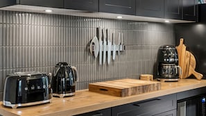 A modern kitchen with a stainless steel range hood, a coffee maker, a toaster, and a knife block on the wall. - Brixton Cottage in Katoomba (Katoomba)