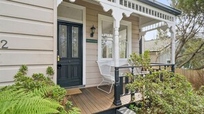 A house with a black front door, a porch with white railings, and a number '2' on the wall. - Brixton Cottage in Katoomba (Katoomba)