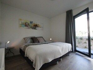 Ein Schlafzimmer mit einem Bett, einem Bild, einem Fenster und Blick ins Freie.