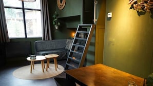 Una sala de estar moderna con un sofá, dos mesitas redondas, una mesa de centro de madera, una escalera y una estantería.