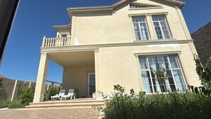 A two-story building with a balcony, large windows, and a covered entrance area. - Spacious 4-bedroom home with air conditioning in beautiful Baku near Miami Beach (Baku)