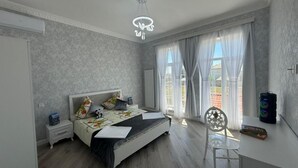 A bedroom with a bed, bedside tables, a desk, a chair, and a window with curtains. - Spacious 4-bedroom home with air conditioning in beautiful Baku near Miami Beach (Baku)