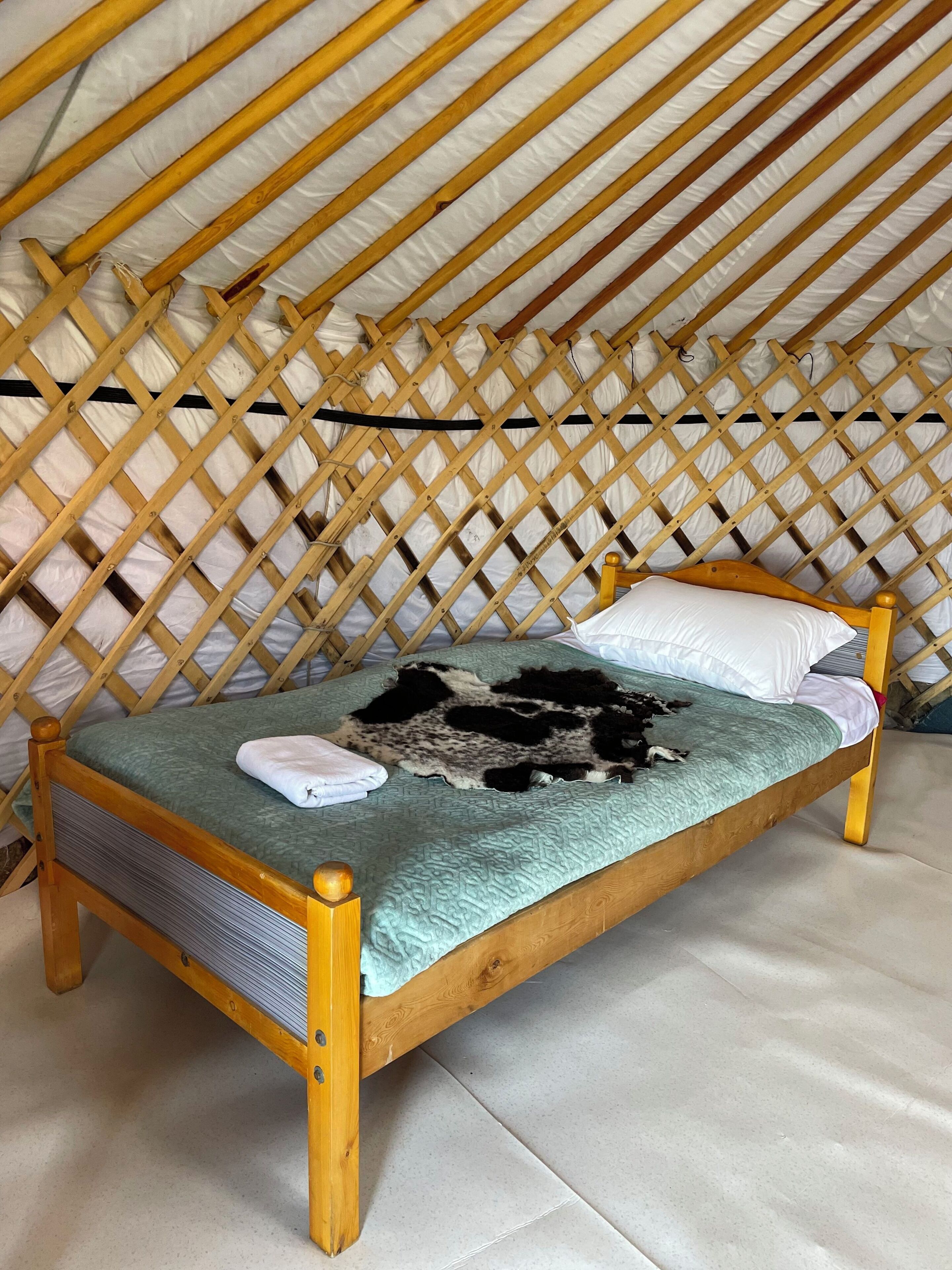 Ein hölzernes Bett mit einer grünen Bettdecke und einer Decke, in einem Zimmer mit einer Holzbodenverkleidung.