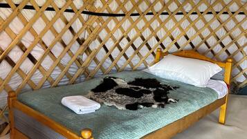 Ein hölzernes Bett mit einer grünen Bettdecke und einer Decke, in einem Zimmer mit einer Holzbodenverkleidung.