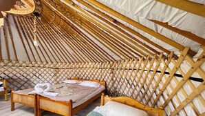 Una carpa acogedora de madera con una cama, almohadas y una manta.