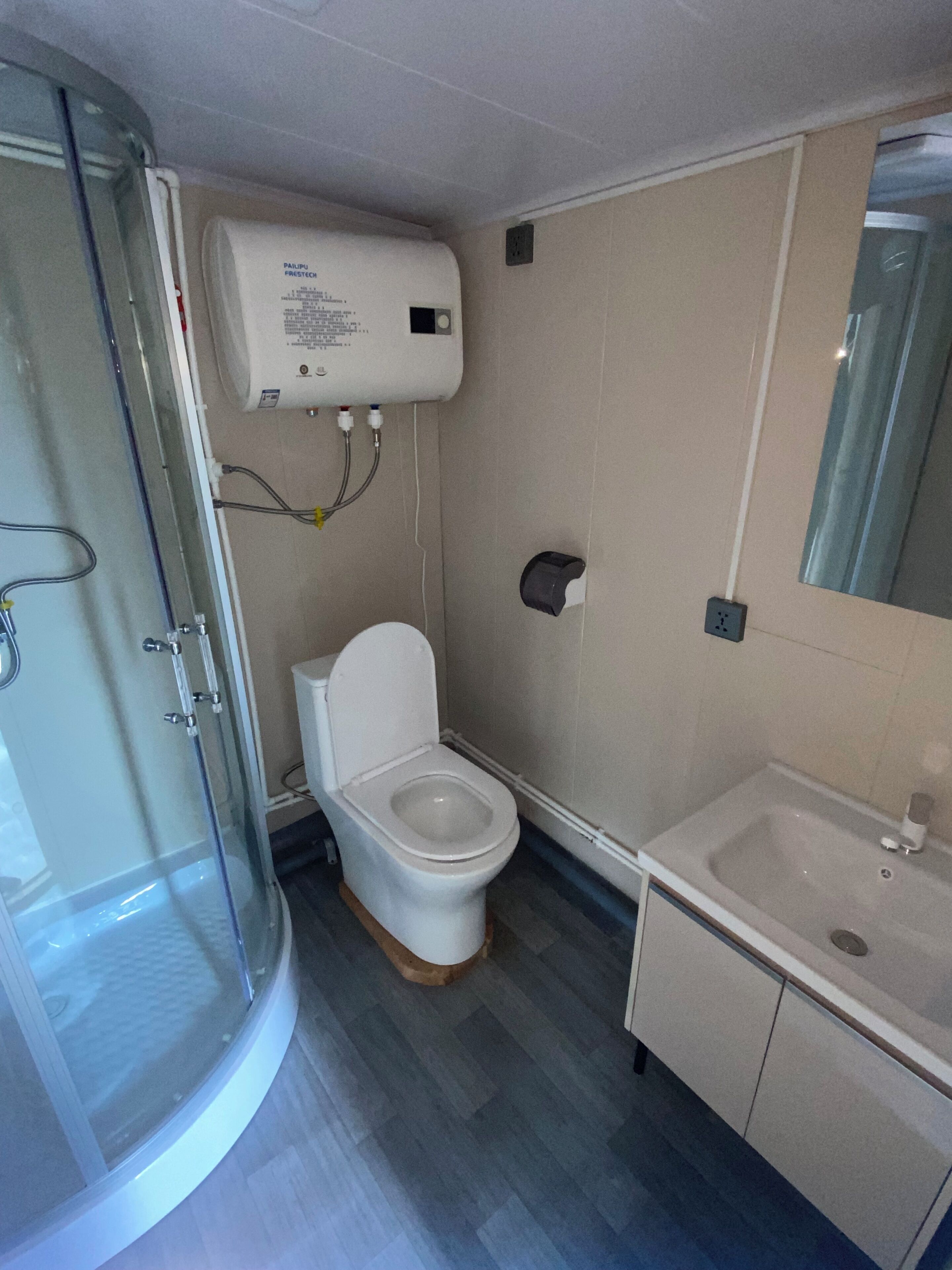 Ein Badezimmer mit Toilette, Waschbecken, Duschkabine und Wandheizung.