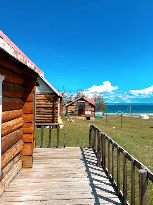 A wooden cabin with a deck and a view of the sea.