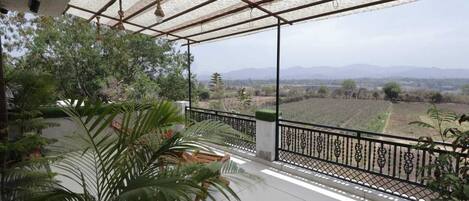 A covered balcony with a view of a rural landscape.