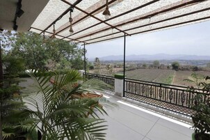A covered balcony with a view of a rural landscape.