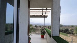 En balkong med utsikt över ett lantligt landskap, en krukväxt och en pergola.