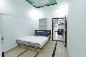 A bedroom with a bed, a ceiling fan, a window with blinds, and a door leading to another room.