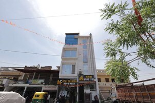 A multi-story building with various shops on the ground floor, including a men's wear store and a home stay service.
