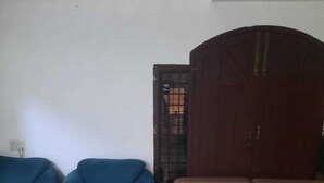 Una habitación con un sofá azul, un sofá marrón, suelo de mármol y un armario.