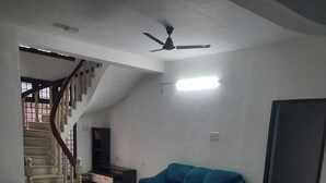Amplia sala de estar con escalera, ventilador de techo y un sofá azul.