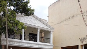Un edificio de dos pisos con un balcón, una entrada con reja y dos scooters estacionados.