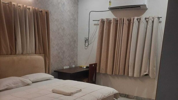 Un dormitorio con cama, mesita de noche, aire acondicionado y cortinas.