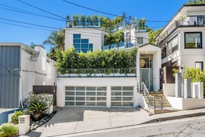 Ein modernes, zweistöckiges Haus mit Garage, einem begrünten Balkon und blauem Himmel.