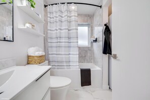 Ein modernes Badezimmer mit Duschvorhang, Toilette, Badewanne und Handtuchhalter.